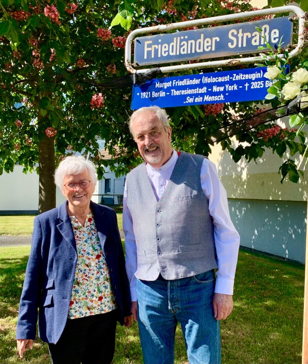 Andrea Stockmayer (Magistrat) und Wolf-Dietrich von Verschuer (beide B 90/DIE GRÜNEN) unter dem Schild der Friedländer Straße. Margot Friedländer (Holocaust-Zeugin) *1921 Berlin - Theresienstadt - New York - ✝ 2025 Berlin "Sei ein Mensch."
